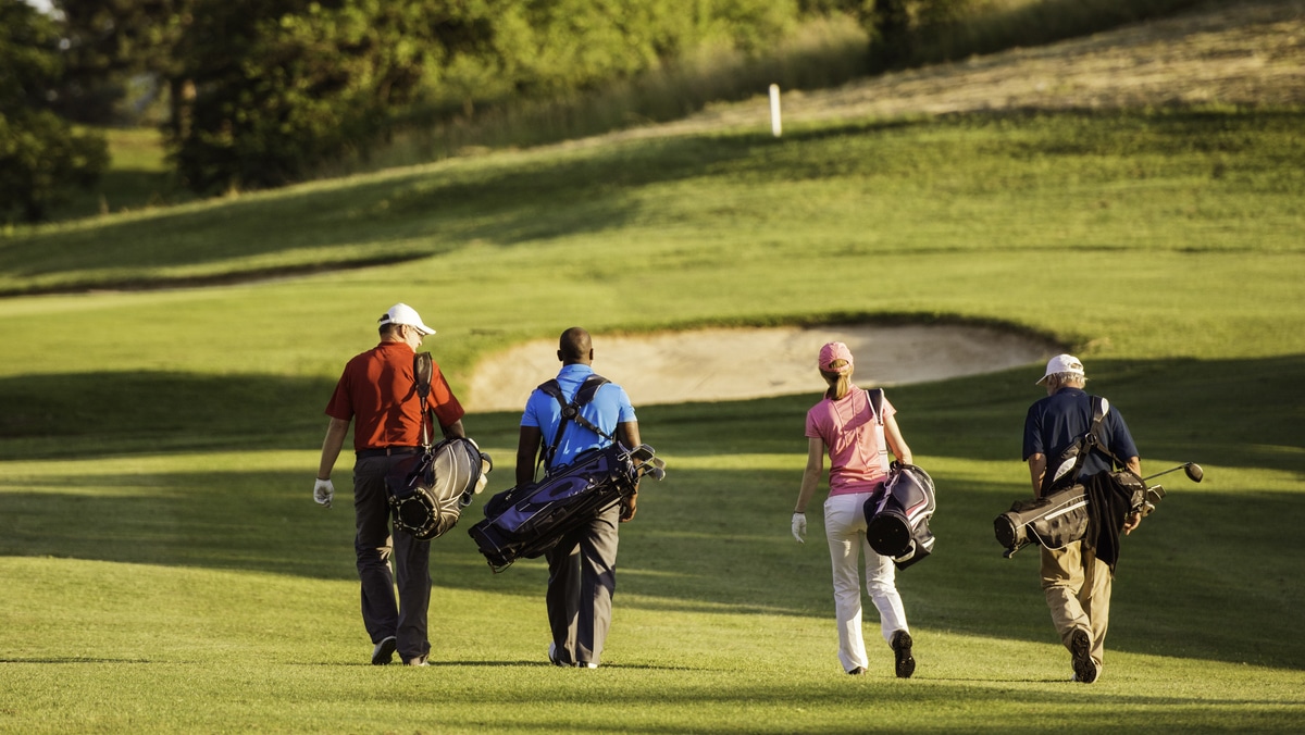 Four friends walking down a golf course together on their buddies trip