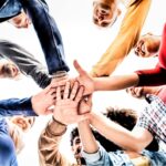 This Is A Photo Of A Group Of Coworkers Putting Their Hands Together.
